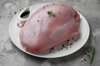 Çiğ hindi göğsü, soya sosu ve gri desenli masada biber.