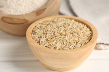 Kahverengi pirinç ve un beyaz ahşap masada, yakın plan.