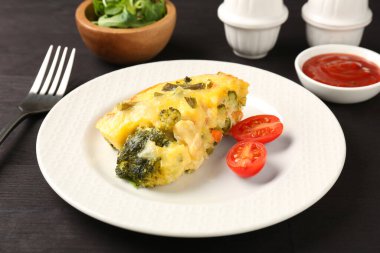 Lezzetli sebze güveci ve siyah ahşap masada domates, yakın plan.