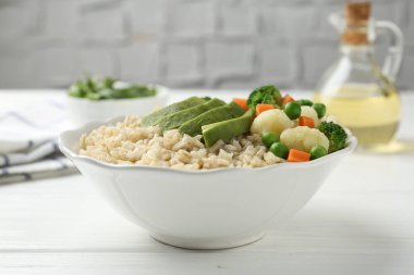 Lezzetli kahverengi pirinç, kasede sebzeler, beyaz tahta masa, yakın plan.