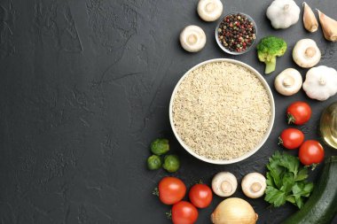 Tabaktaki çiğ kahverengi pirinç taze ürünlerin arasında koyu dokulu masada, düz yerde. Metin için boşluk