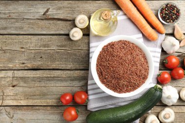 Tabaktaki çiğ kahverengi pirinç ahşap masadaki taze ürünlerin arasında, düz yerde. Metin için boşluk