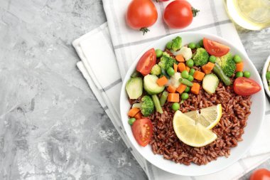 Gri desenli masada servis edilen sebzeli ve limon dilimli lezzetli kahverengi pirinç. Metin için boşluk