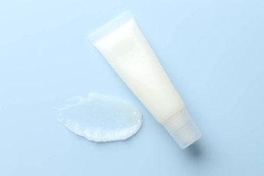 Açık mavi arkaplanda nemlendirici dudak kremi ve tüp, üst görünüm