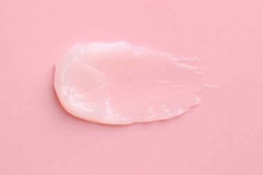 Pembe arka planda nemlendirici dudak kremi, üst manzara.