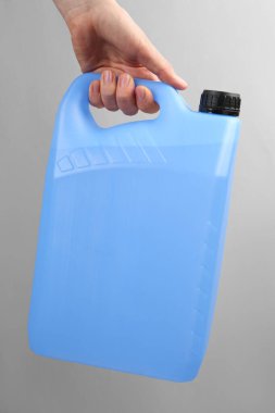 Açık gri arka planda antifriz kutusu olan kadın, yakın plan.