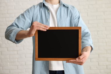 Kapalı alanda boş küçük tahta tutan adam, yakın plan.