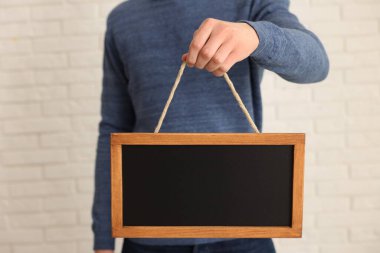 Kapalı alanda boş küçük tahta tutan adam, yakın plan.