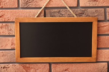 Tuğla duvarda boş küçük bir tahta.