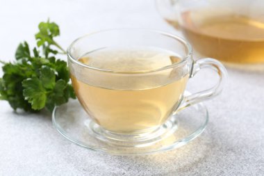 Cam bardakta Aromatik bitki çayı ve açık gri masada taze maydanoz, yakın plan.