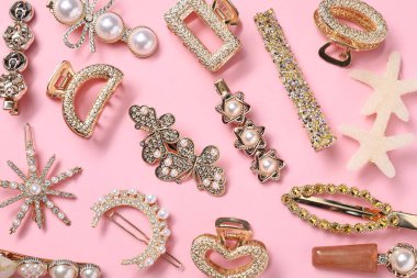 Different hair clips on pink background, flat lay