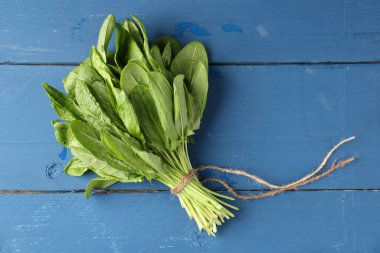 Mavi ahşap masanın üstünde taze yeşil defne yaprakları var. Metin için boşluk