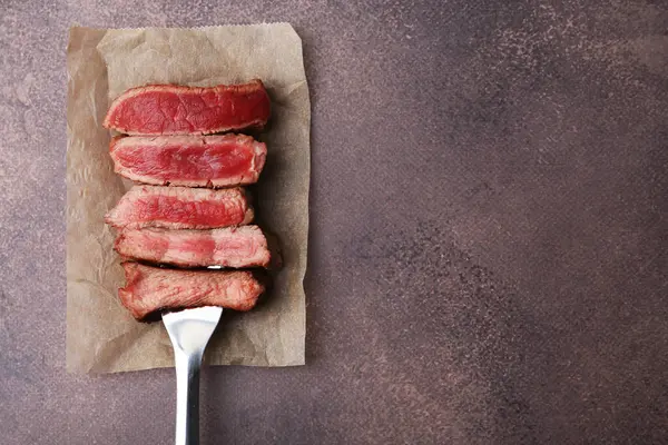 Lezzetli dilimlenmiş sığır filetosu. Kahverengi desenli masa, üst manzara. Metin için boşluk