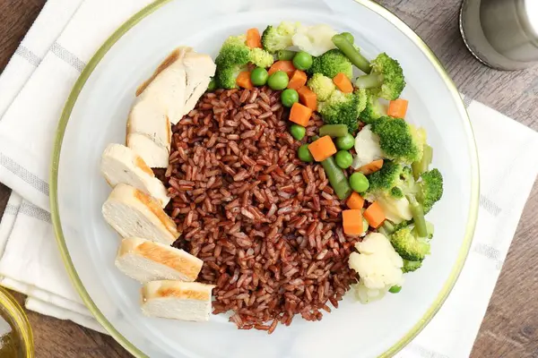 Tahta masada servis edilen tavuk ve sebzeli lezzetli kahverengi pirinç.