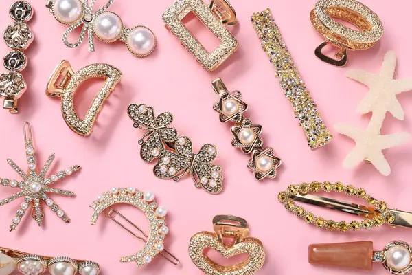 Different hair clips on pink background, flat lay