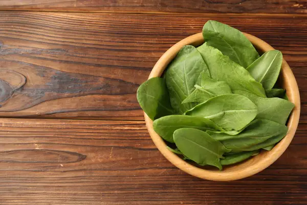 Tahta masadaki kasede taze yeşil kuş yaprakları, üst manzara. Metin için boşluk