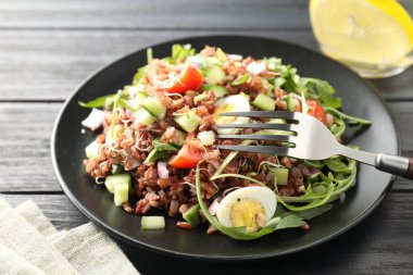 Siyah ahşap masada kahverengi pirinçli leziz salata, yakın plan.