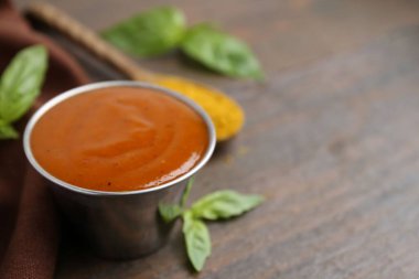 Metal tabakta lezzetli köri sosu, ahşap masada toz ve fesleğen, yakın plan. Metin için boşluk