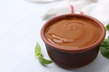 Lezzetli köri sosu ve fesleğen yaprakları beyaz fayanslı masada, yakın plan. Metin için boşluk