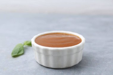 Lezzetli köri sosu ve fesleğen yaprakları gri masada, yakın plan. Metin için boşluk