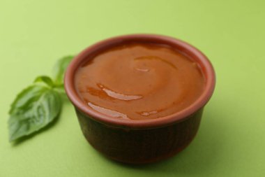 Yeşil arka planda lezzetli köri sosu ve fesleğen yaprakları, yakın plan.