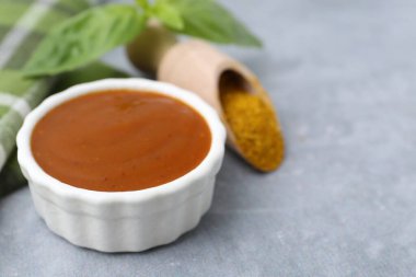 Lezzetli köri sosu, toz ve fesleğen yaprakları gri masada, yakın plan. Metin için boşluk