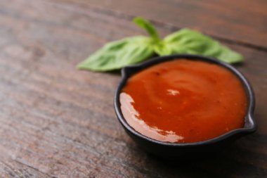 Lezzetli köri sosu ve fesleğen yaprakları ahşap masada, yakın plan. Metin için boşluk