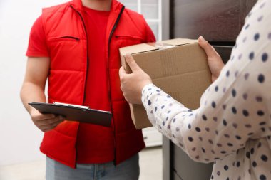 Elinde dosya olan kurye içerideki alıcıya paket veriyor, yakın plan.