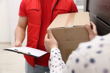 Elinde dosya olan kurye içerideki alıcıya paket veriyor, yakın plan.