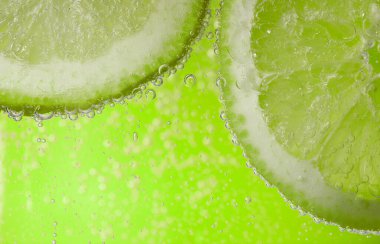 Açık yeşil arka planda limon dilimli soda, yakın plan.