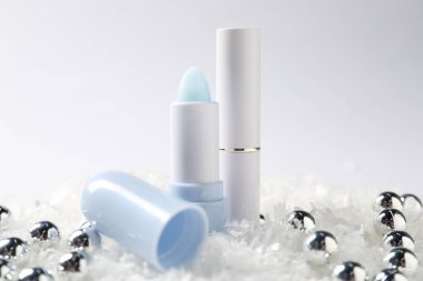 Nemlendirici dudak kremleri ve yapay kar üzerine Noel süslemeleri beyaz arka planda, yakın plan. Kış bakımı