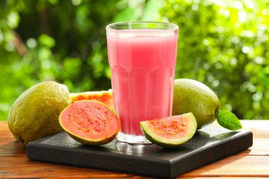 Guava suyunu tazeliyorum ve ahşap masada taze meyveler, yakın plan.