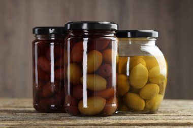 Ahşap masada cam kavanozlarda turşulu zeytin, yakın plan.