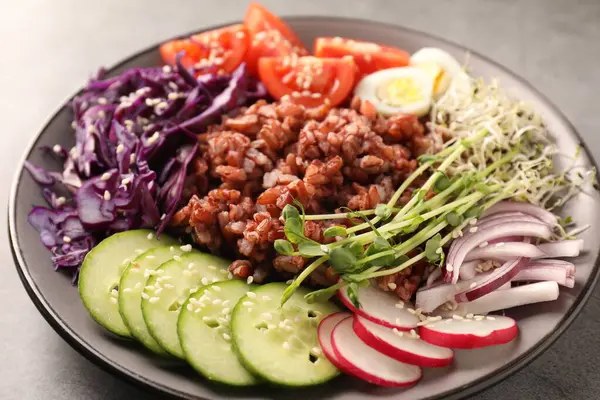 Gri masada kahverengi pirinçli lezzetli salata, yakın plan.