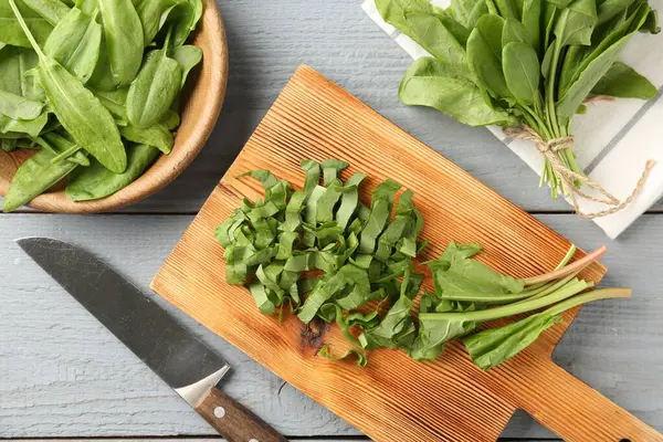 Gri ahşap masada taze kuş yaprakları ve bıçak kes, düz uzan.