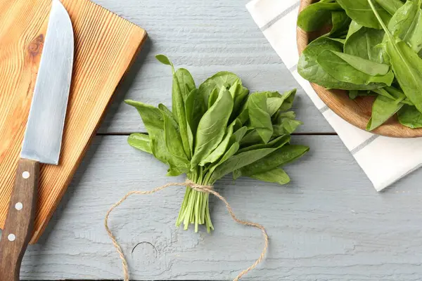 Taze kuş yaprakları ve bıçak gri ahşap masada, düz yatıyordu.