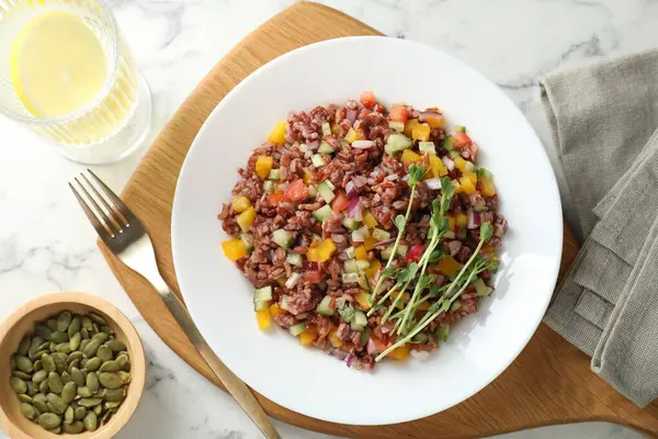 Beyaz mermer masada servis edilen kahverengi pirinçli lezzetli salata.