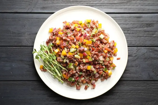 Siyah ahşap masada kahverengi pirinçli lezzetli bir salata.