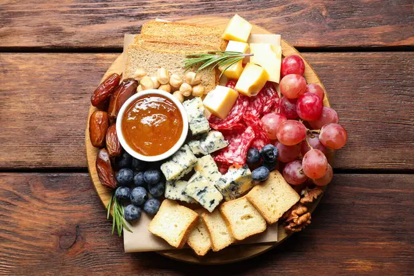 Tahta masa ve üst manzara üzerinde çeşitli lezzetli peynir ve diğer atıştırmalıklar.