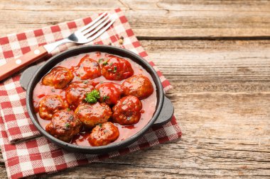 Ahşap masadaki fırın kabında domates soslu leziz köfteler, yakın plan. Metin için boşluk