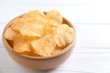 Lezzetli patates cipsleri beyaz ahşap masada, yakın plan. Metin için boşluk