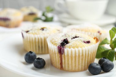 Yaban mersinli lezzetli kekler, pudra şekeri ve nane şekeri beyaz masada, yakın plan.