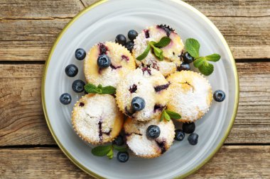 Yaban mersinli lezzetli çörekler, pudra şekeri ve nane şekeri ahşap masa, üst manzara
