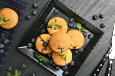 Yaban mersinli lezzetli kekler, nane ve çatal bıçak seti koyu dokulu masa, düz uzanmış.