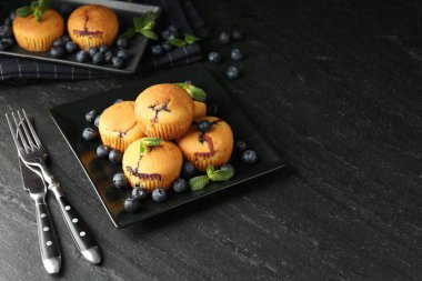 Yaban mersinli lezzetli kekler, nane ve çatal bıçak seti koyu dokulu masa. Metin için boşluk