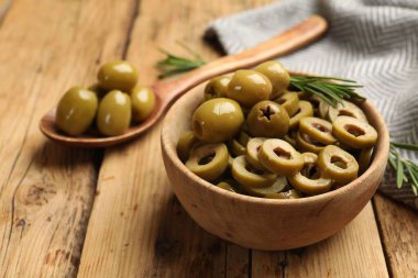 Lezzetli zeytin halkaları kasede, kaşıkta ve biberiyede ahşap masada, yakın plan.