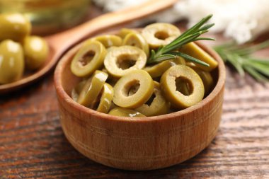 Lezzetli marine edilmiş zeytin halkaları ve biberiye ahşap masada, yakın plan.