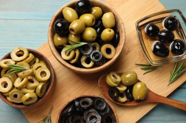 Farklı lezzetlerde marine edilmiş zeytin halkaları, tüm olanlar ve biberiye açık mavi ahşap masa, üst manzara