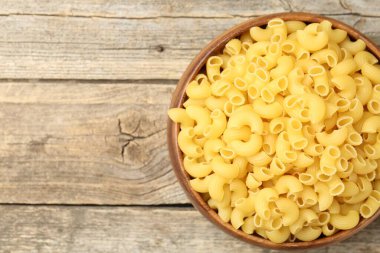 Tahta masadaki kasede çiğ boynuzlu makarna, üst manzara. Metin için boşluk