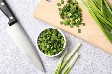 Taze yeşil soğan ve bıçak açık gri masada, düz yatıyordu.